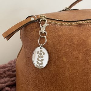 Stylish leather bag with yarn-inspired keychain charm, perfect for crafts and handmade accessories.