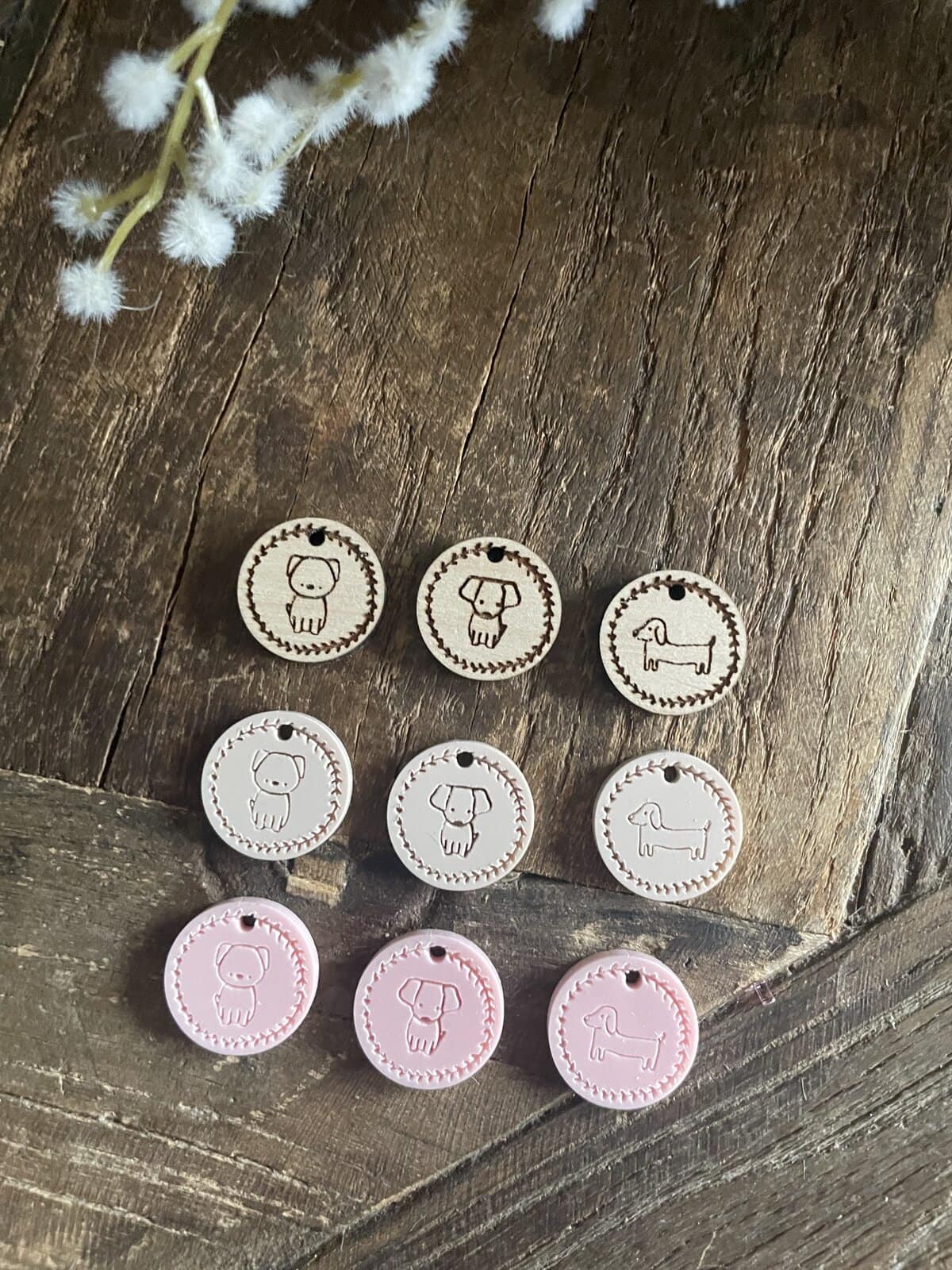 Whimsical wood laser-cut dog and cat tags in pastel pink, white, and natural wood tones for pet personalization.