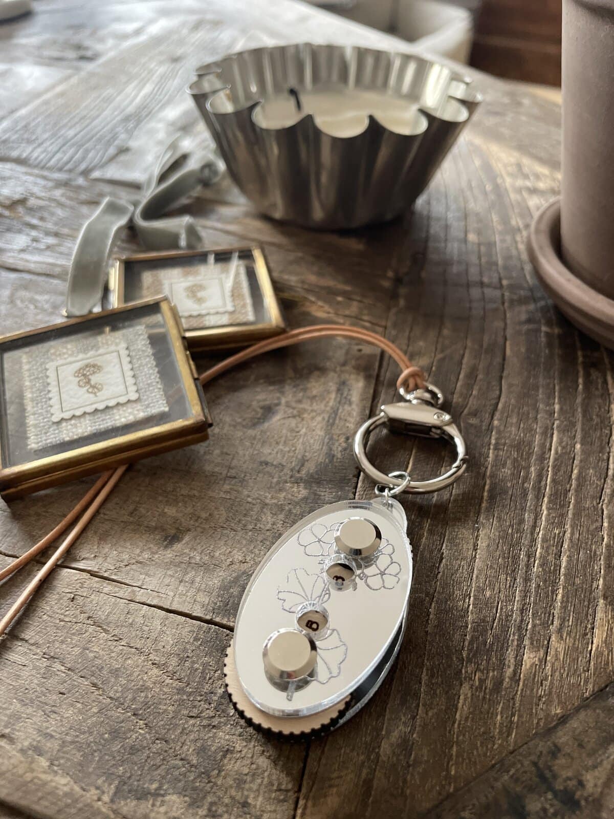 Intricate yarn gauge with floral engraving on rustic wooden table, surrounded by crafting tools and materials.
