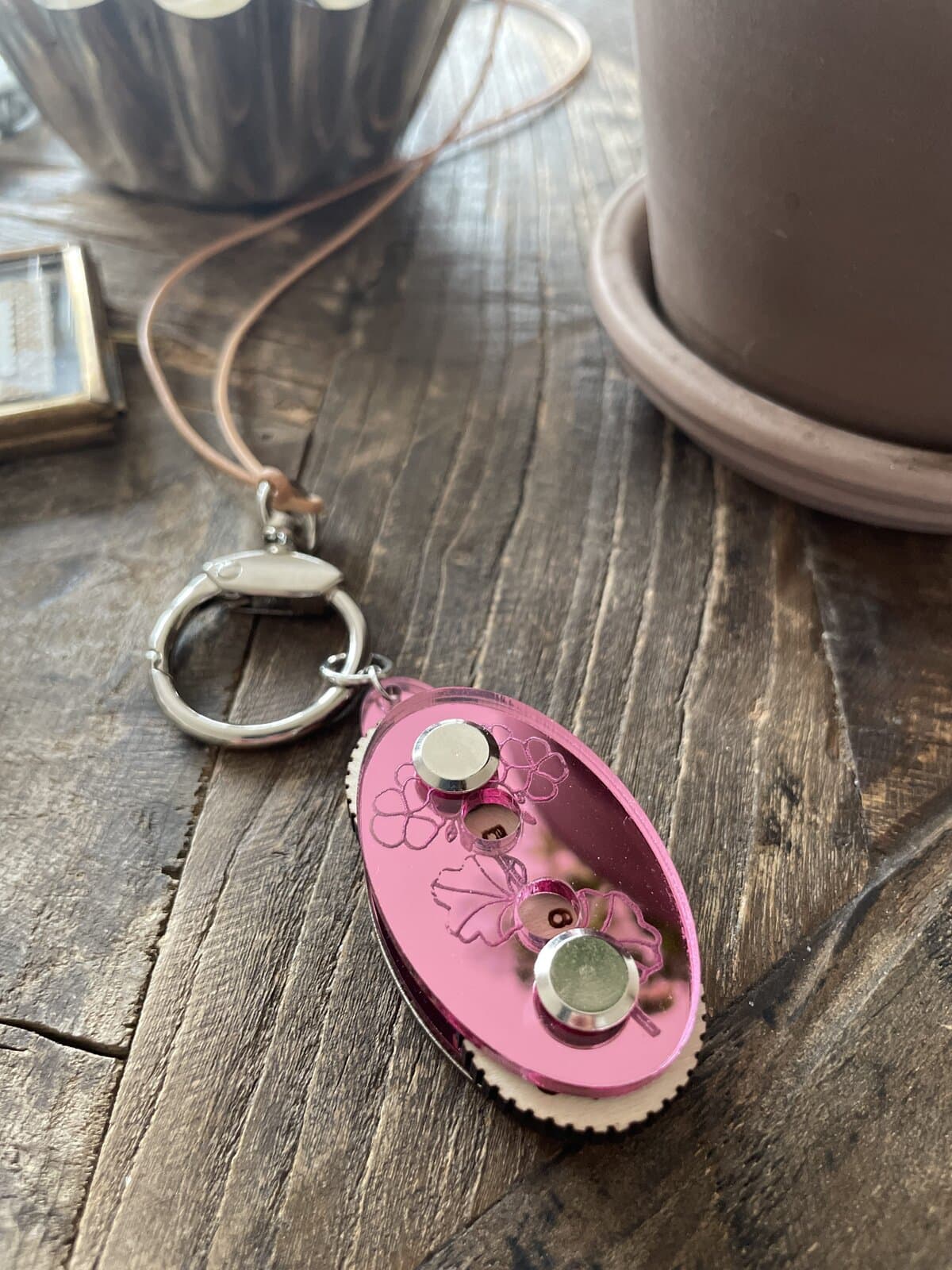Colorful floral-themed keychain with metallic accents on a rustic wooden surface.