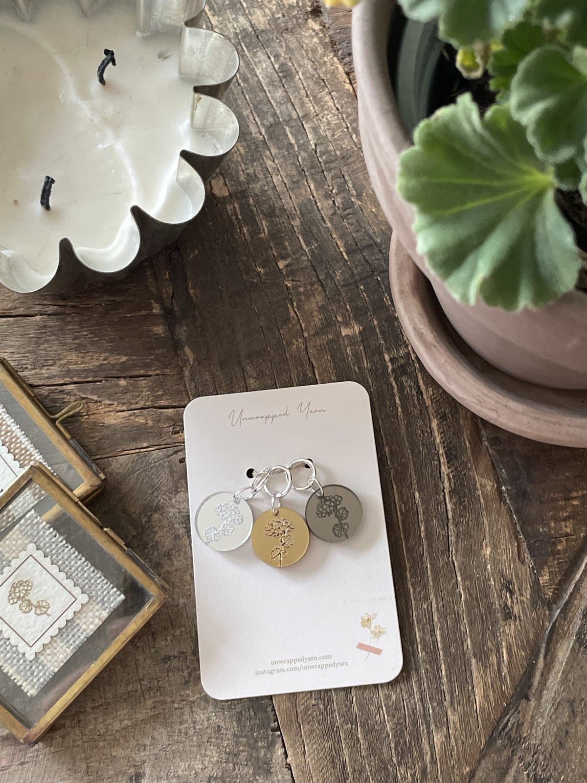 Silver and gold engraved charm keychain with floral design, displayed on a white card from Unwrapped Yarn.