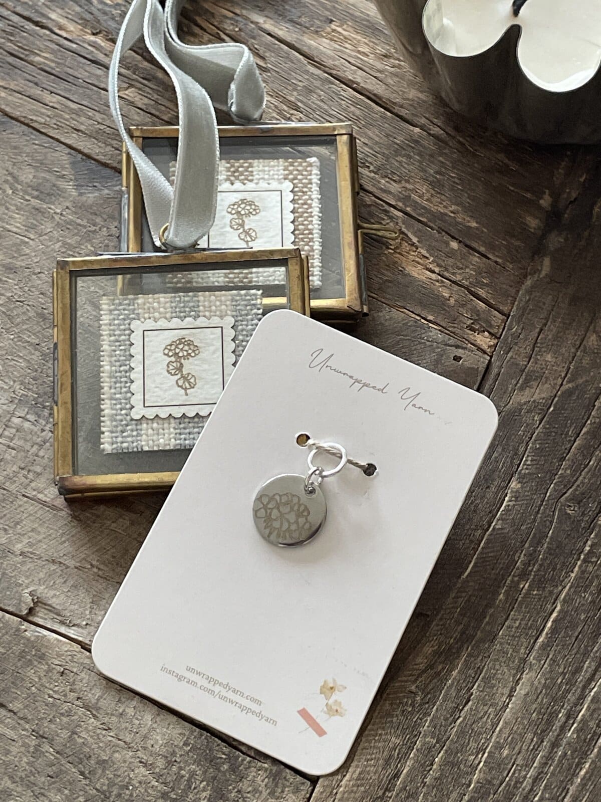 Silver jewelry gift set with engraved flower pendant and earrings, presented on a white card on rustic wood surface.