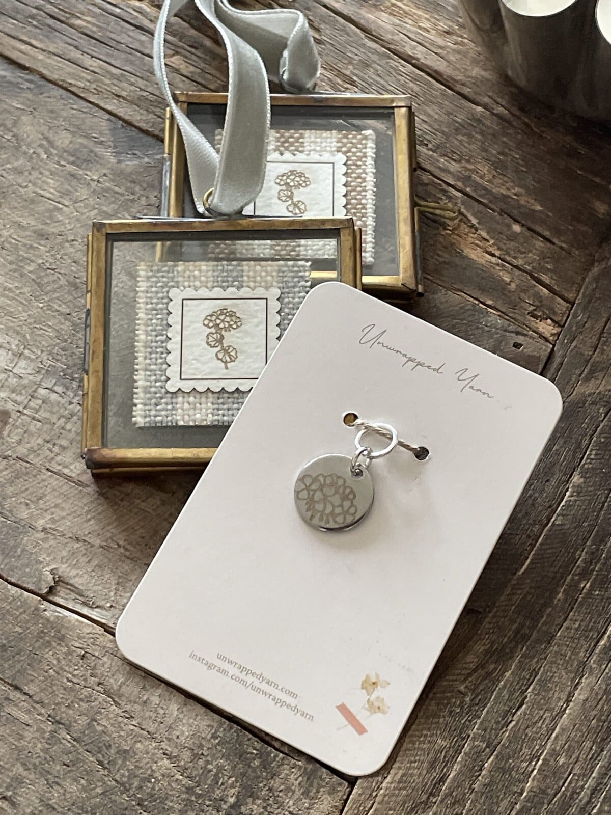 Delicate silver jewelry with handmade yarn motifs displayed on elegant card and cozy wooden surface.