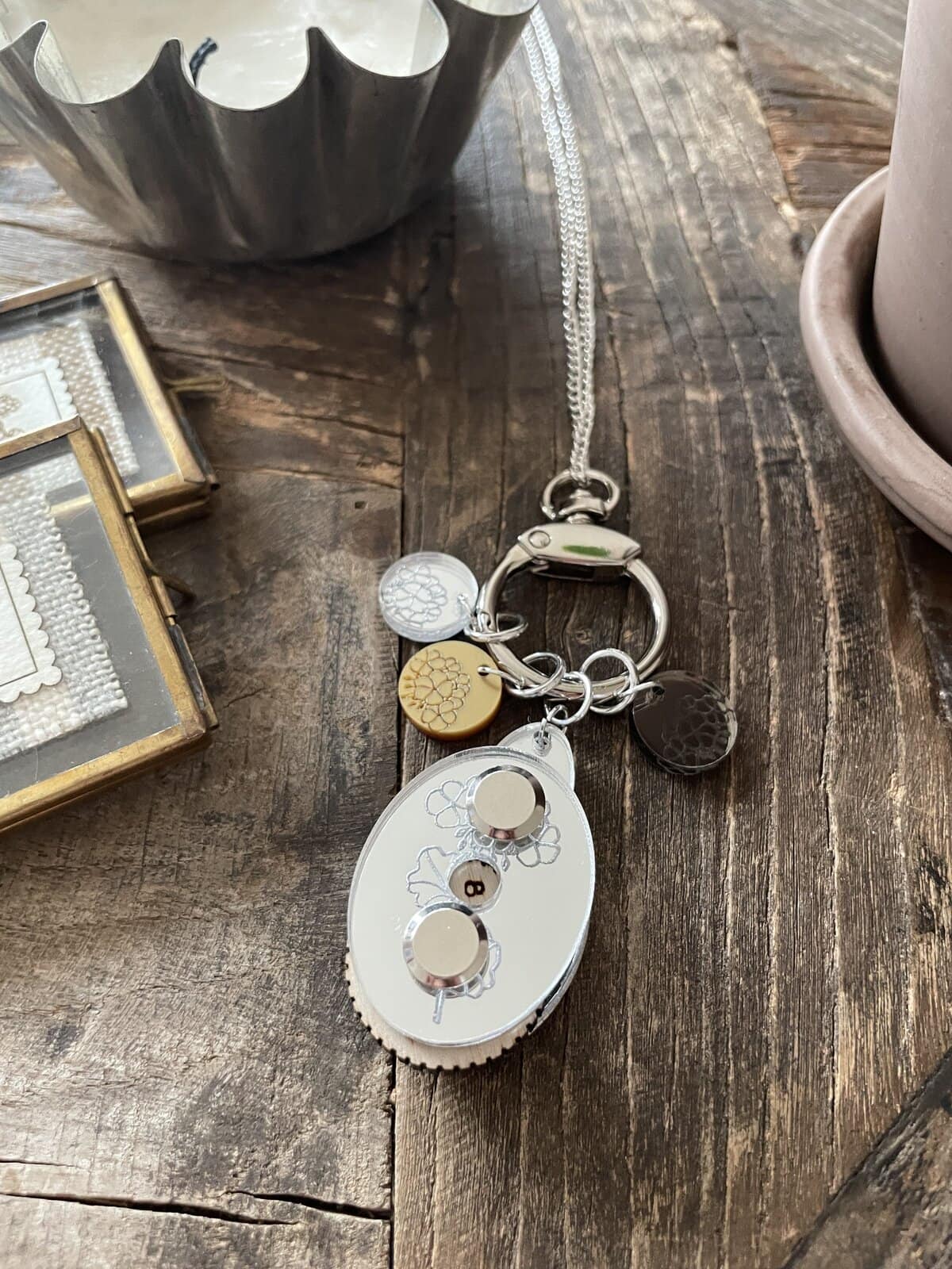 1. Stylish silver and gold charm keychain with floral accents on rustic wooden surface.