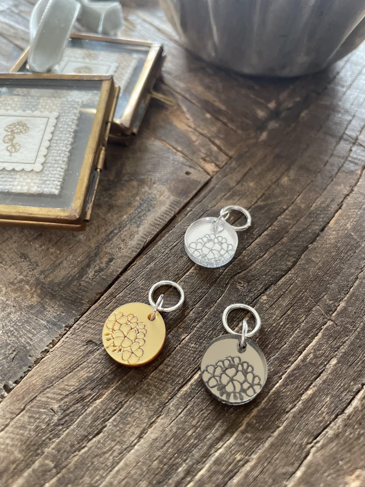 Delicate yarn-inspired jewelry charms on rustic wood surface, artisan craft supplies from Unwrapped Yarn.