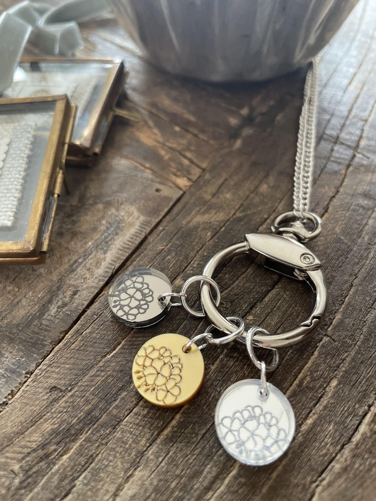 Silver keychain with floral charms on wooden surface, ideal for handmade jewelry and gift accessories.