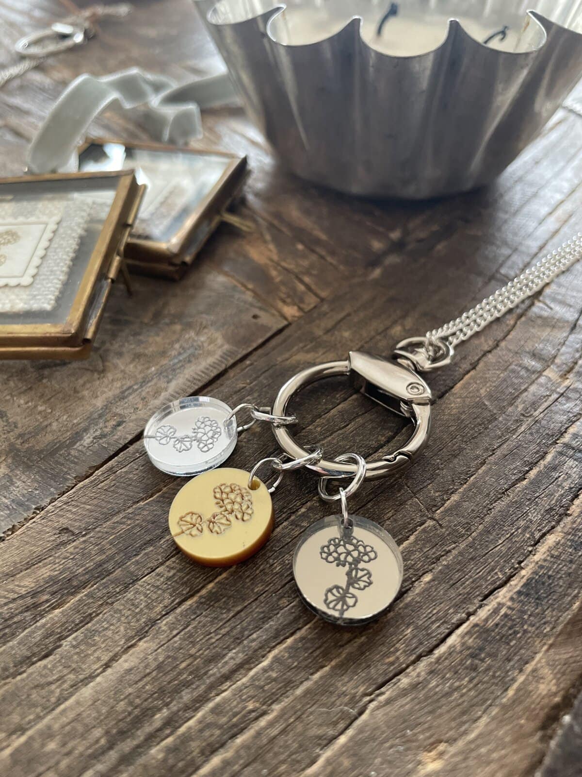 Silver keychain with engraved grapevine charms on rustic wooden surface.