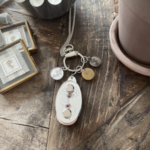 Delicate jewelry and candles displayed on rustic wooden table, emphasizing handmade craftsmanship and elegant design.
