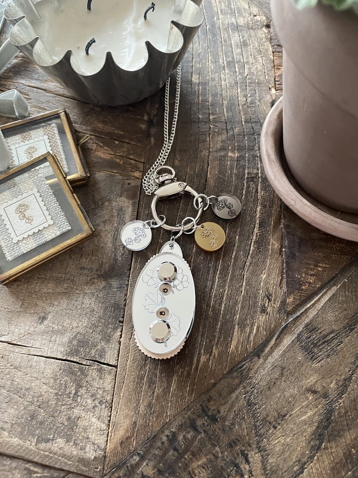 Delicate jewelry and candles displayed on rustic wooden table, emphasizing handmade craftsmanship and elegant design.