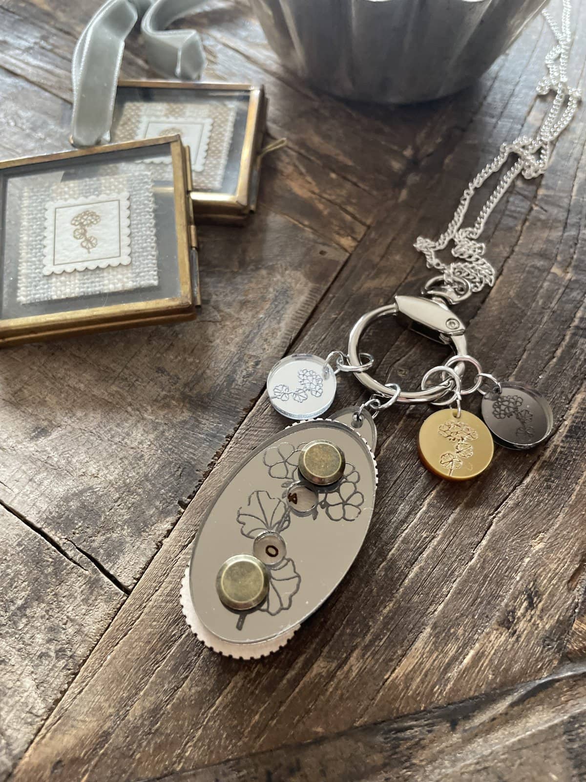 Intricate jewelry keychain with floral engravings, set on rustic wooden surface, showcasing elegant accessories.