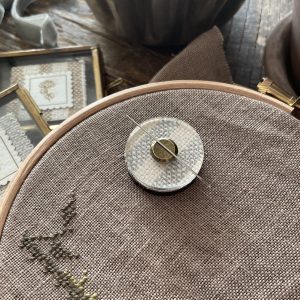 Soft beige embroidery floss on linen fabric, perfect for handmade fiber art projects.