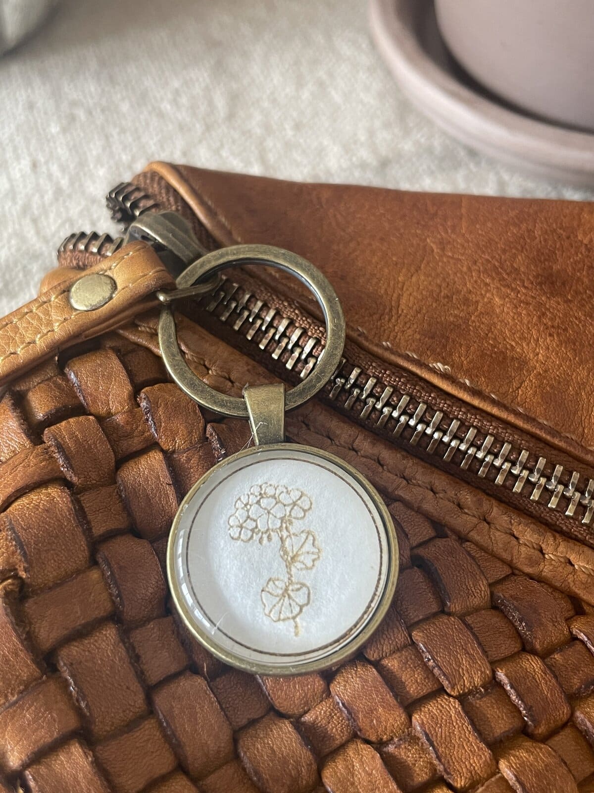 Handwoven leather bag with a decorative keychain, showcasing artisanal craftsmanship and stylish accessories.