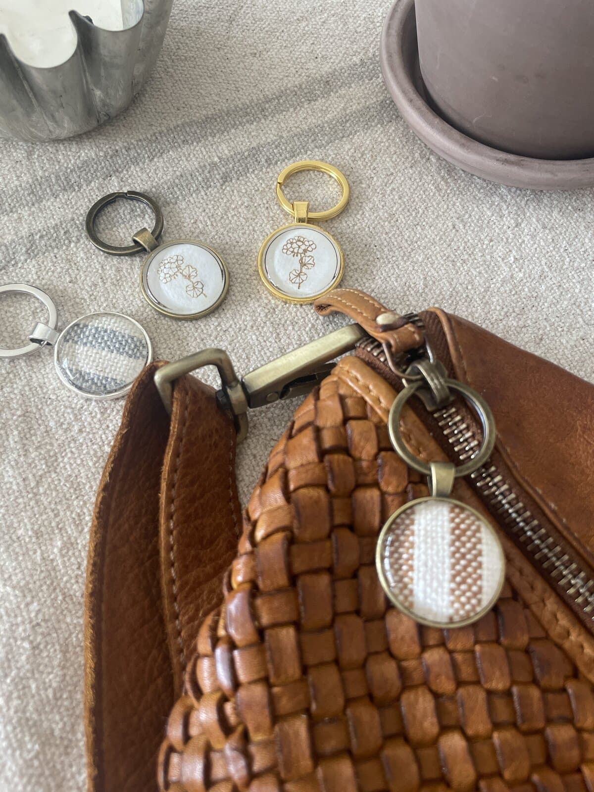 1. Gold, silver, and black keychains with floral embroidery on a textured surface.