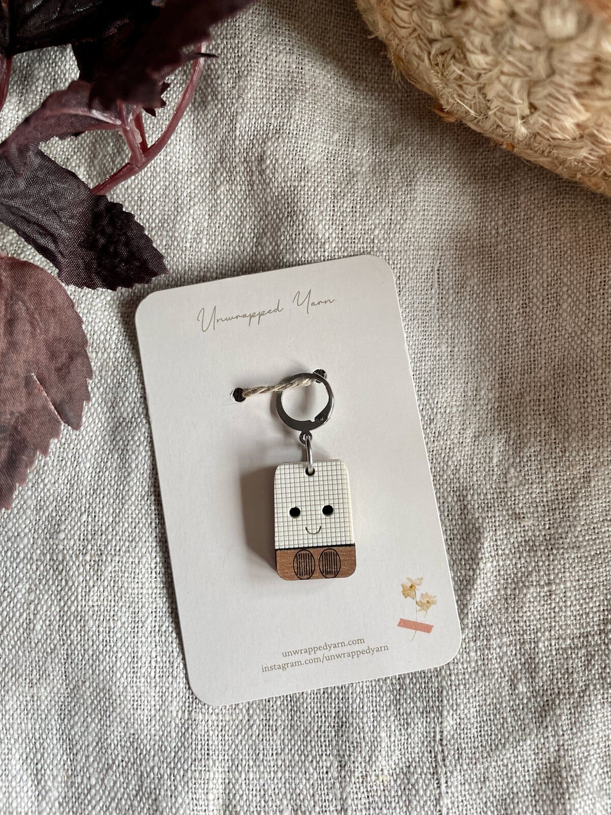 Cute wooden doll keychain with a smiling face and cozy outfit, perfect for yarn and craft enthusiasts.