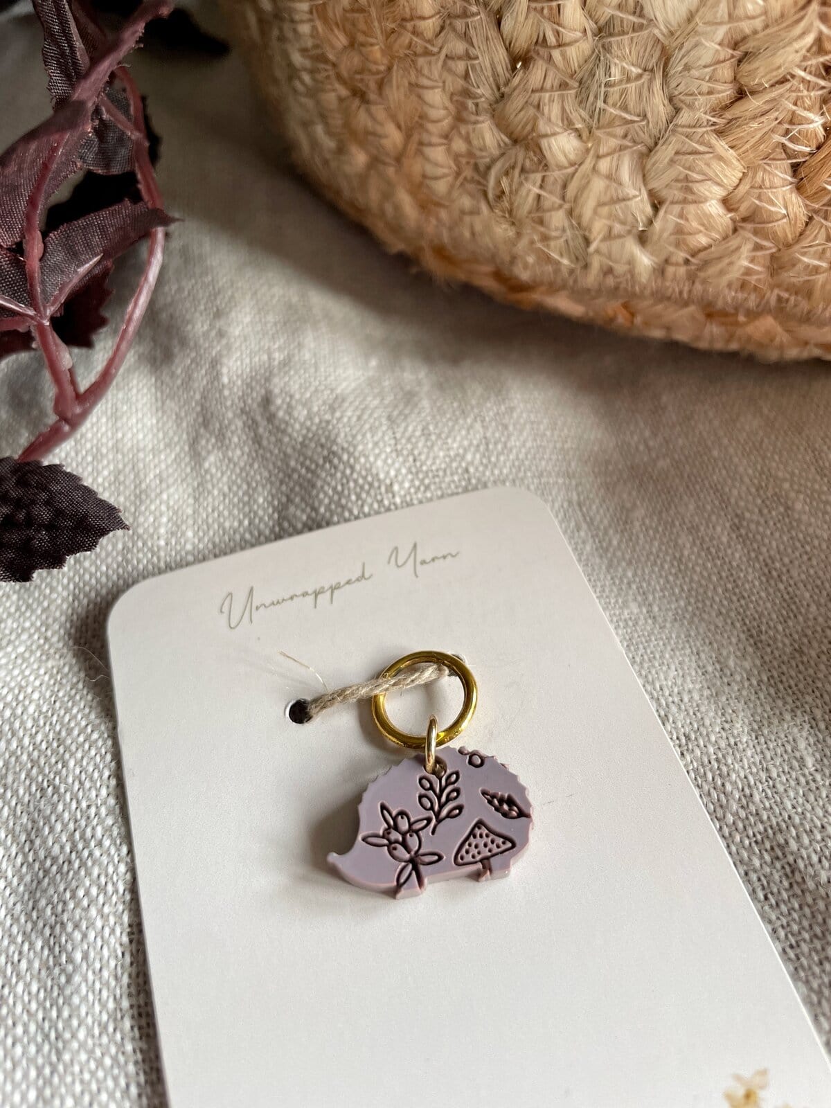 Soft pink yarn charm with botanical and mushroom design on a white jewelry card, ideal for crochet and knitting accessories.