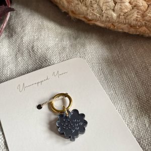 Soft black yarn charm with gold ring, perfect for crochet and knitting accessories.