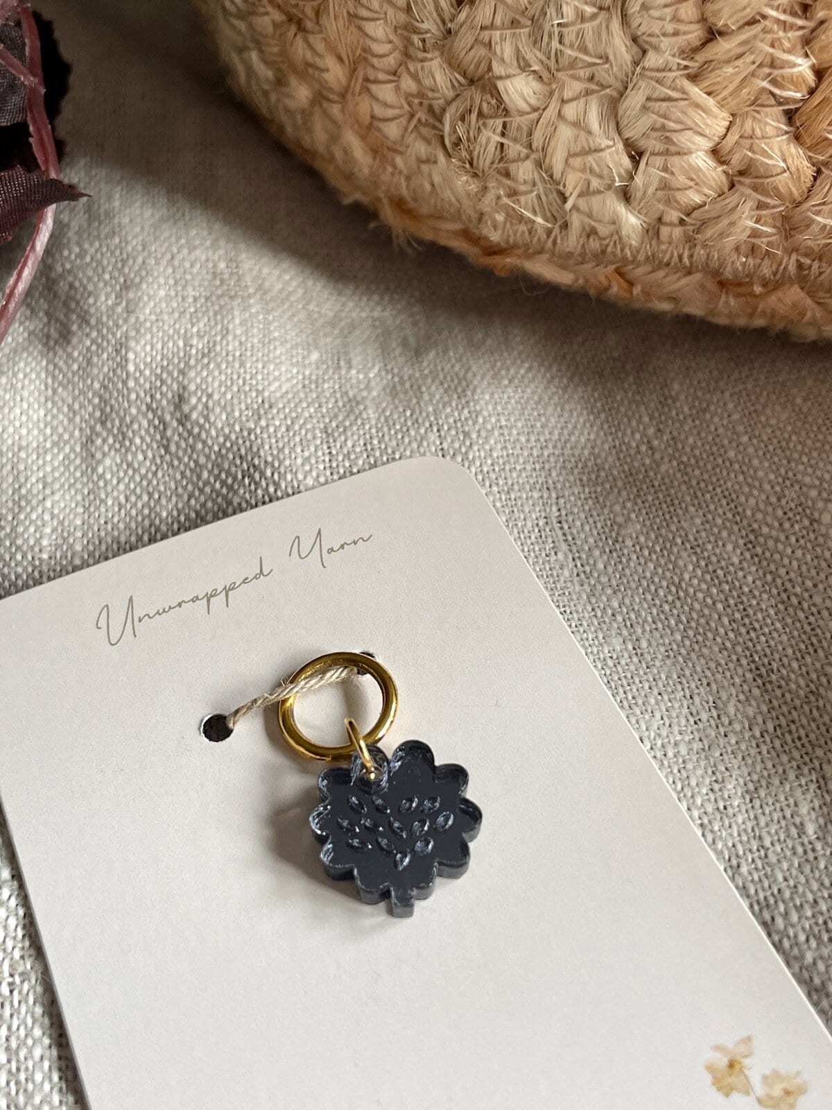 Soft black yarn charm with gold ring, perfect for crochet and knitting accessories.