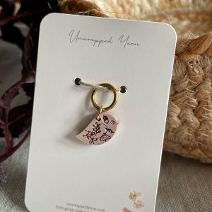 Delicate pink resin charm with floral and bird design, attached to a gold keyring for jewelry or accessories.