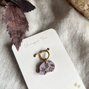 Soft pink resin keychain with floral and mushroom design, on a white card from Unwrapped Yarn.