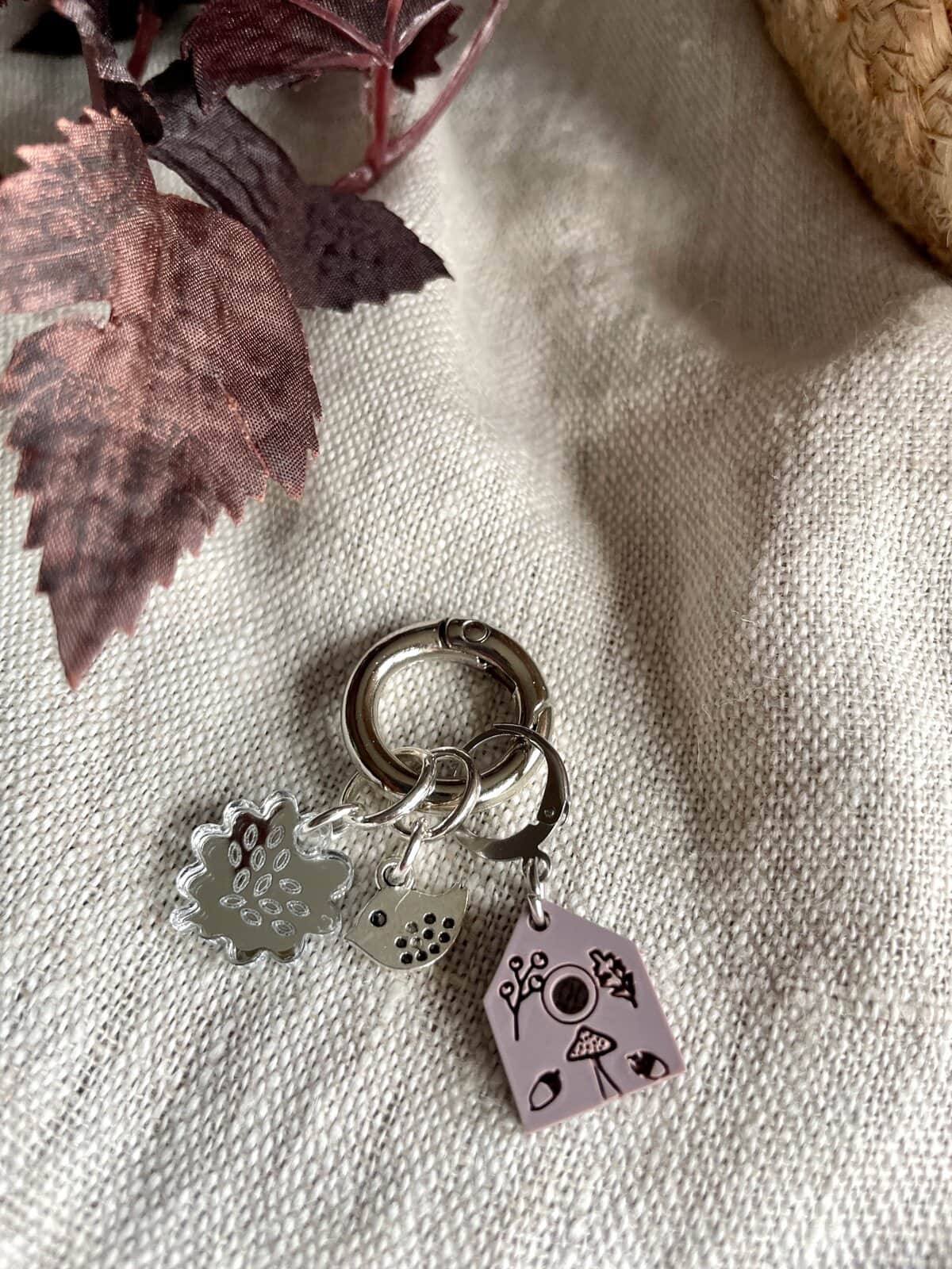 Chic silver keychain with floral, ladybug, camera, and house charms for jewelry and accessories.