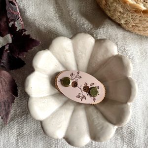 Bright white ceramic scalloped dish with decorative jewelry on natural linen background.