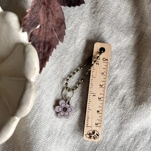 Colorful flower keychain accessory with beaded chain on neutral fabric background.