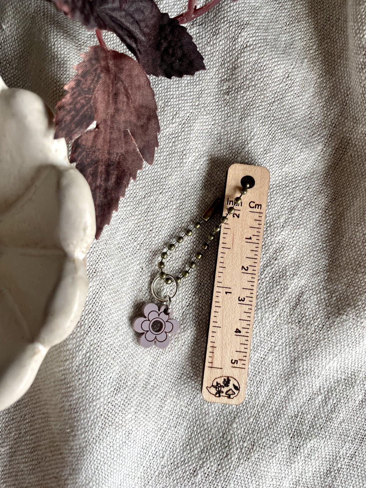 Colorful flower keychain accessory with beaded chain on neutral fabric background.