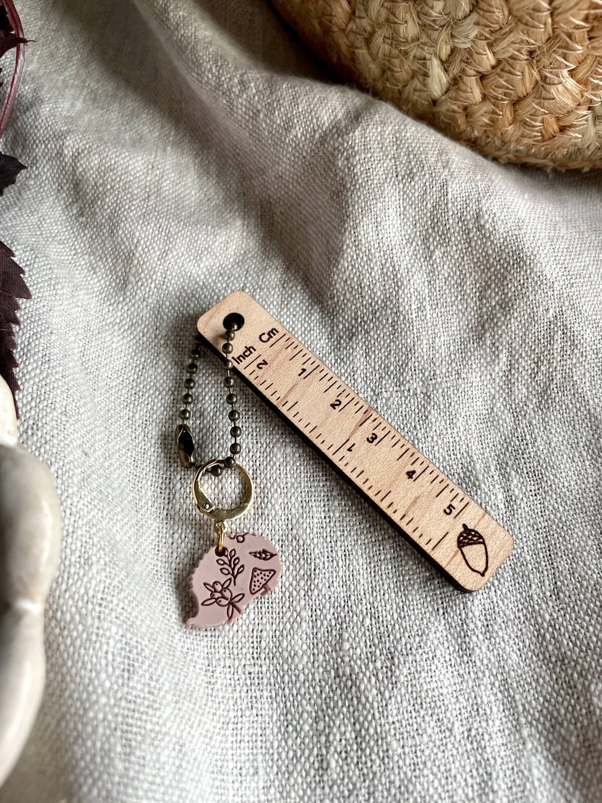 Soft pink sewing project zipper pull with floral design on a linen fabric background.