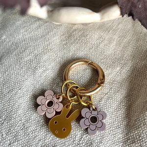 Colorful bunny and flower charms keychain on beige fabric.