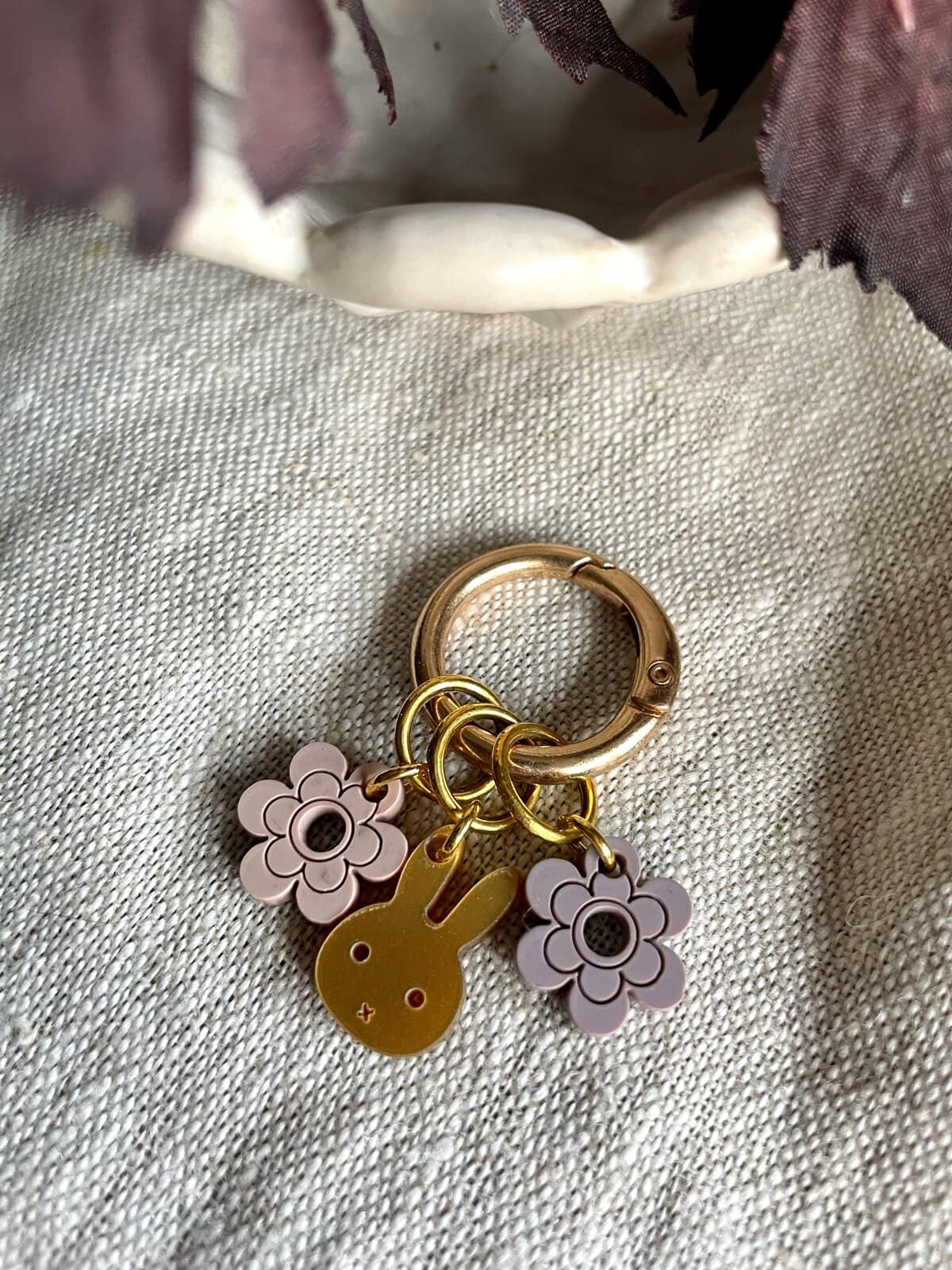 Colorful bunny and flower charms keychain on beige fabric.
