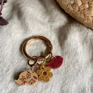 Colorful charm keychain with floral and nature-inspired designs on beige fabric.