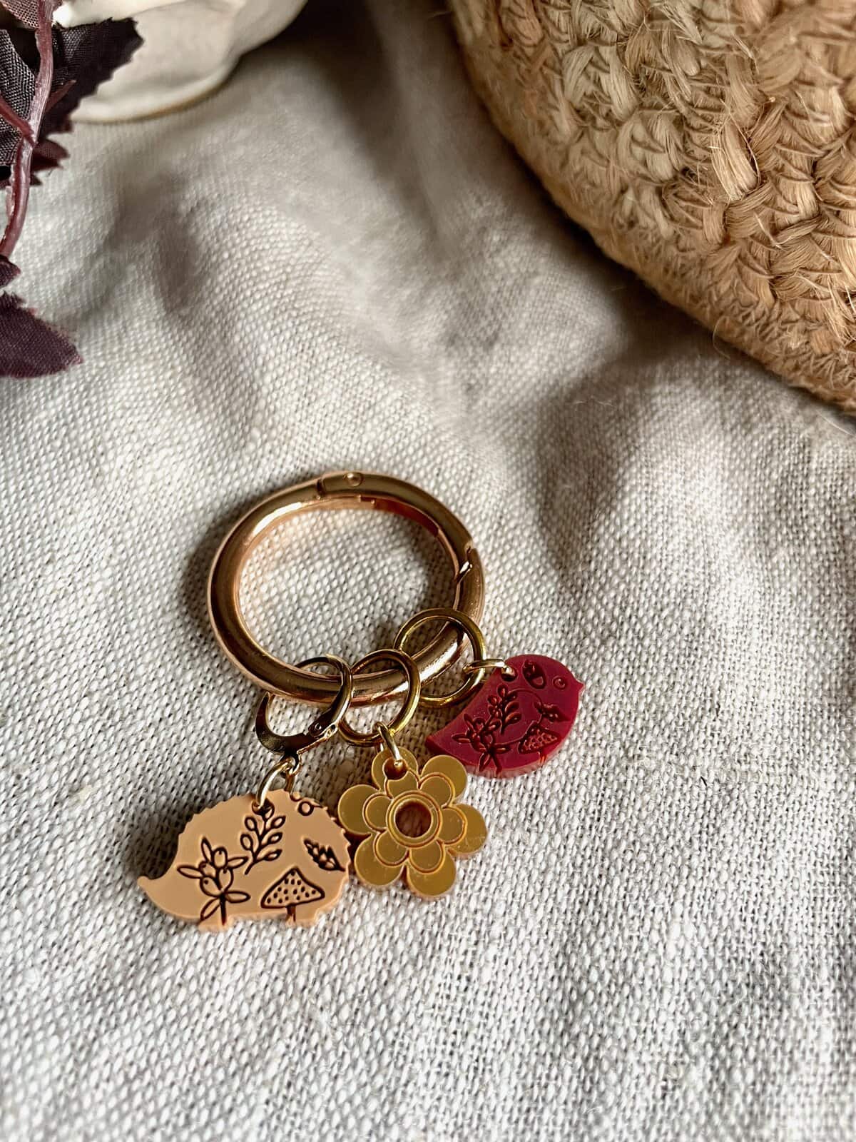 Colorful charm keychain with floral and nature-inspired designs on beige fabric.