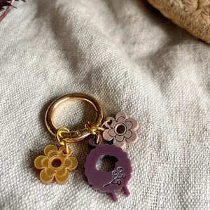 Colorful flower and key-shaped acrylic keychain on fabric, trendy accessory for yarn enthusiasts.