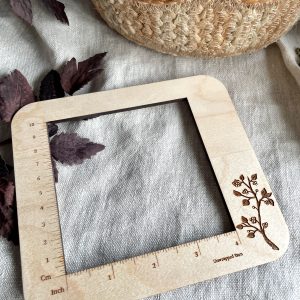 Softwood measuring frame with engraved floral design, ideal for yarn and knitting projects.