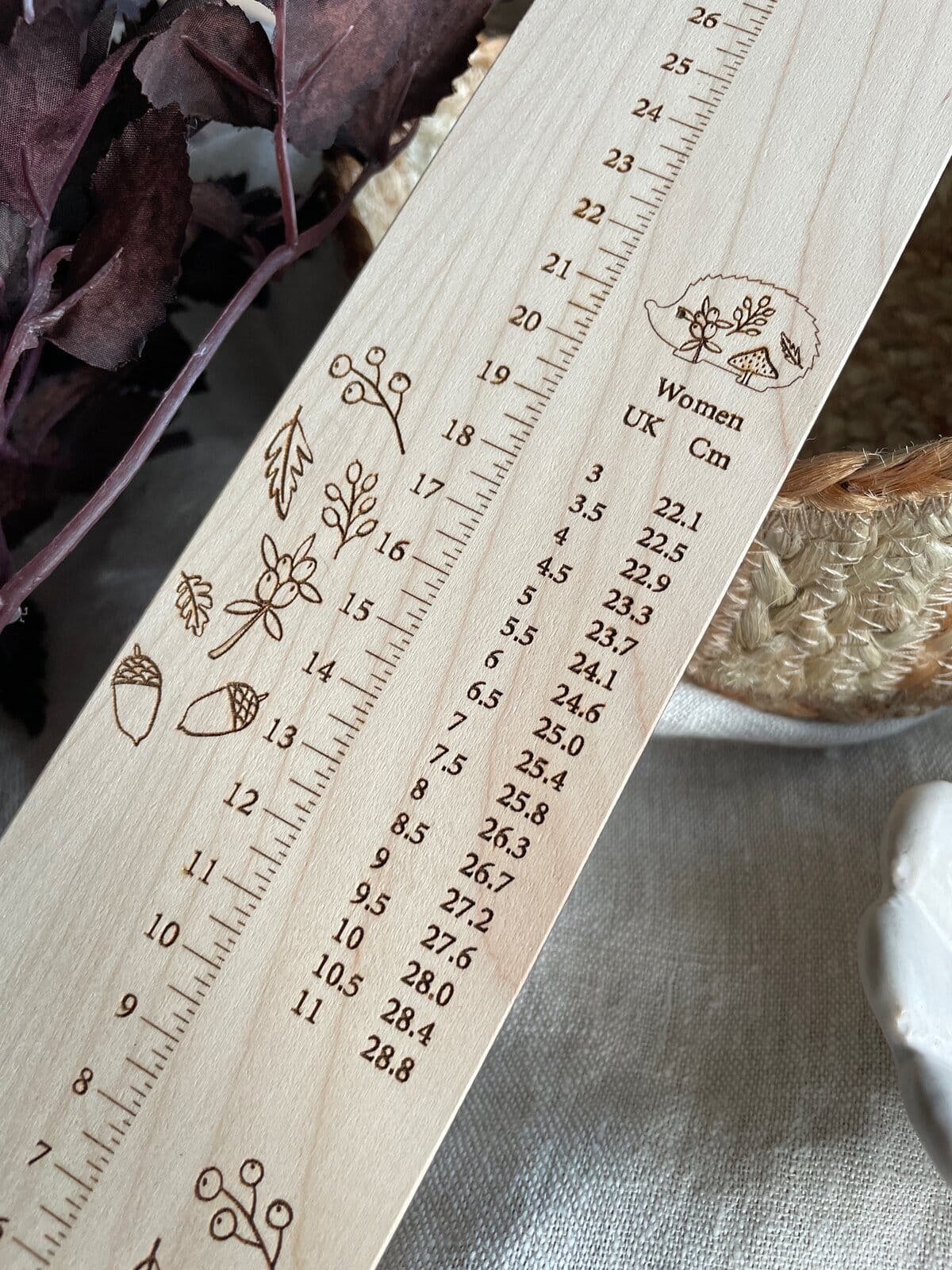 Handmade wooden yarn gauge with floral and natural motifs, perfect for knitting and craft projects.