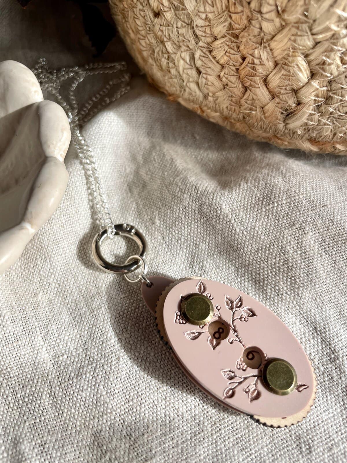 Soft pink yarn keychain with floral design and brass accents, perfect for knitting or crochet enthusiasts.