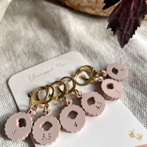 Pink knitting needle gauge tags with measurement sizes on a keyring.