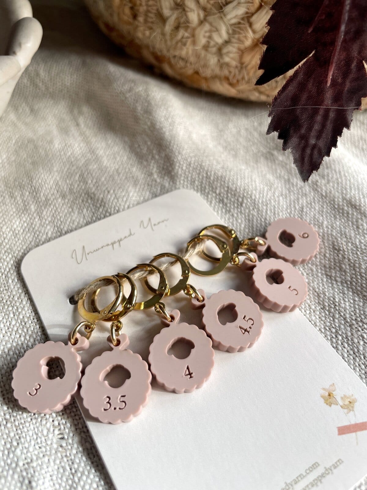 Pink knitting needle gauge tags with measurement sizes on a keyring.