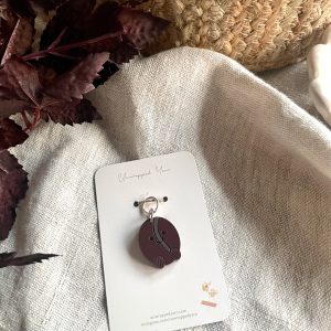 Colorful yarn with a charm accessory on a white tag, surrounded by natural decor, perfect for knitting and crochet projects.