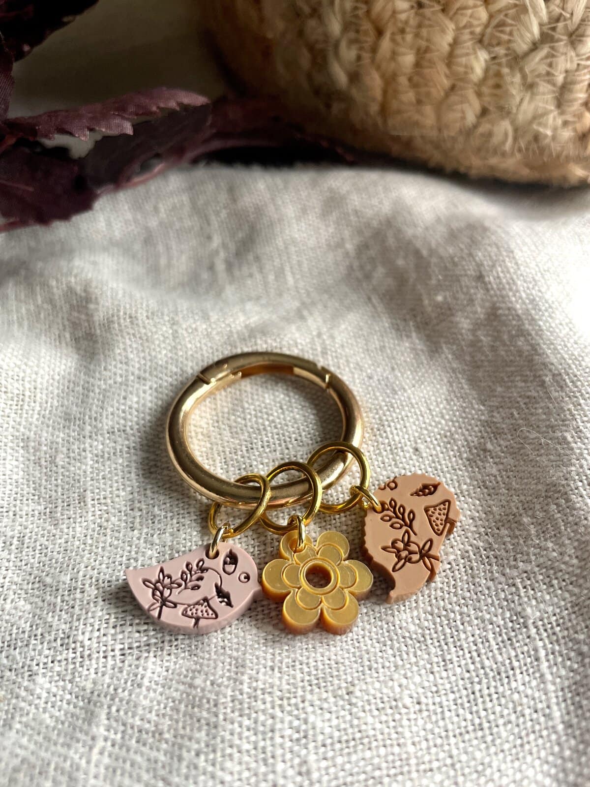 Colorful jewelry keychain with floral and animal charms on white fabric.