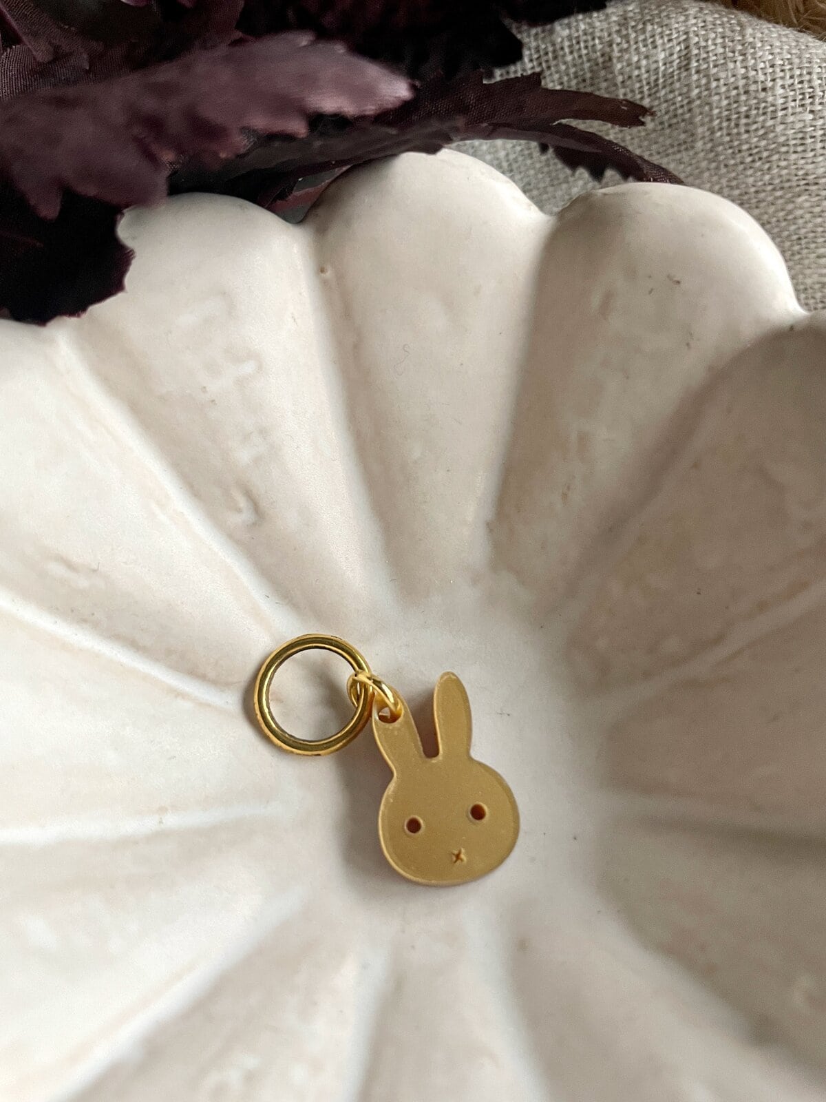 Delicate gold bunny keychain on a textured white ceramic dish, showcasing cute jewelry for accessory lovers.