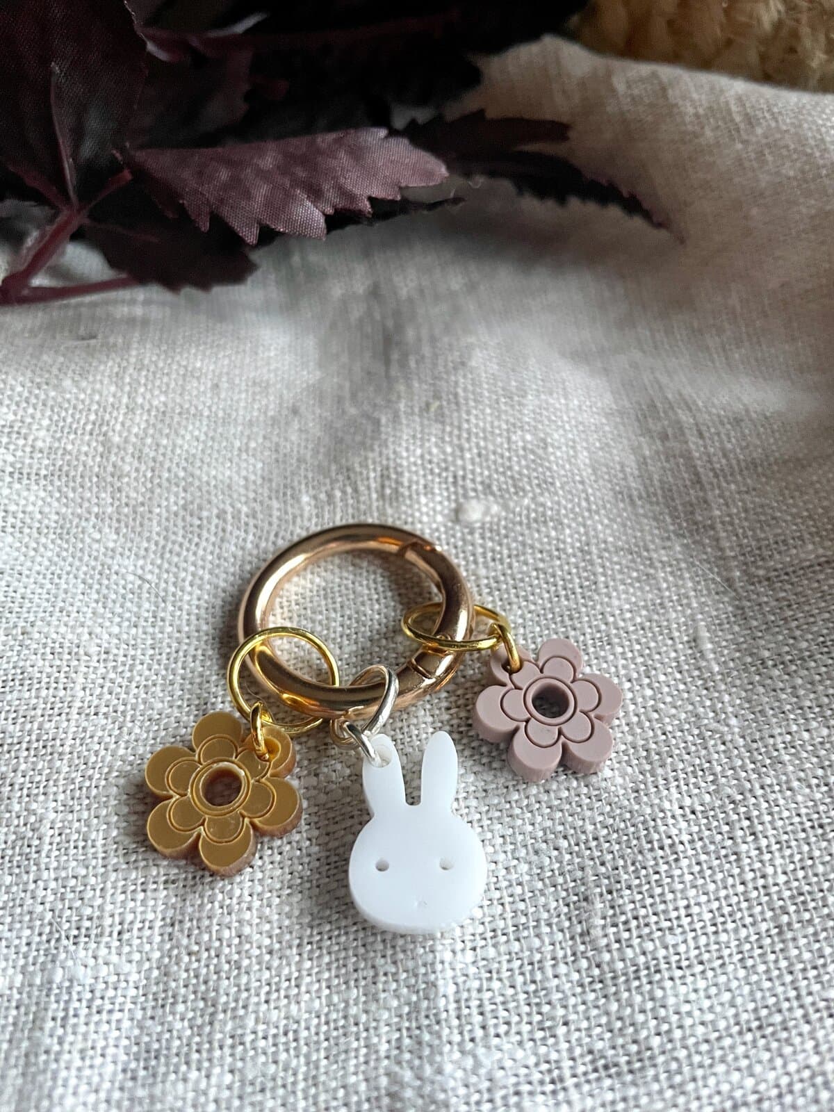 Colorful keychain with floral and bunny charms on textured fabric background.