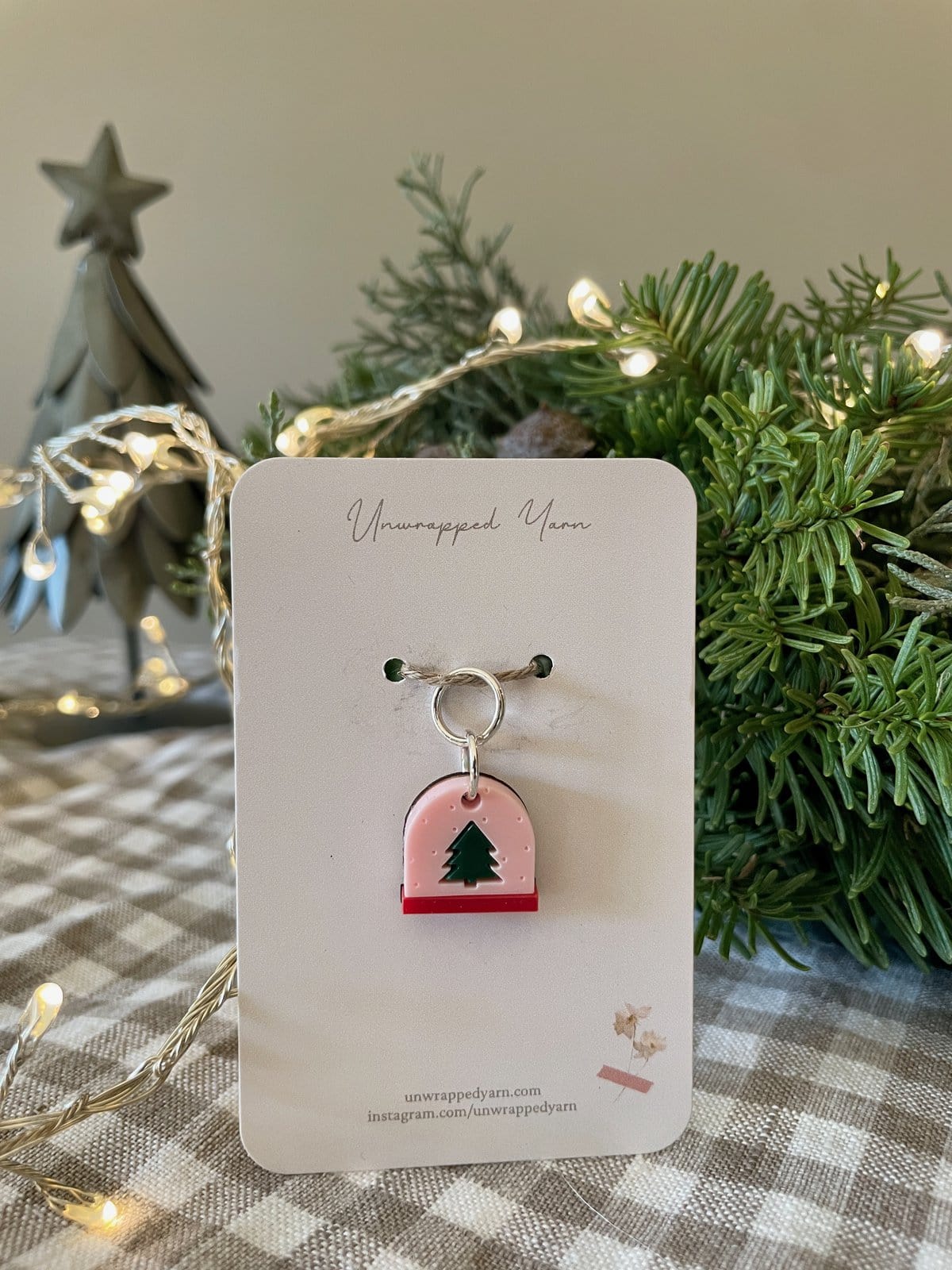 Festive holiday tree ornament with a green Christmas tree charm on a pink background, ideal for Christmas decor.