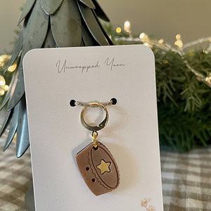Miniature brown yarn-themed charm jewelry, perfect for knitting or crochet enthusiasts.