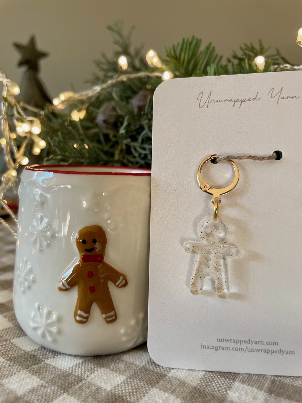 Small gingerbread man keychain with glitter on transparent yarn, displayed on a white card.