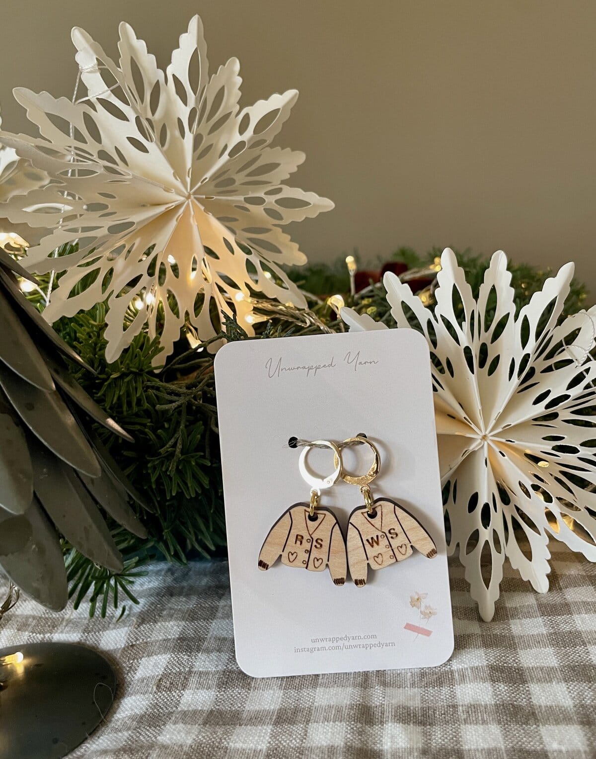 Delicate wooden angel earrings with engraved letters on a white jewelry card.