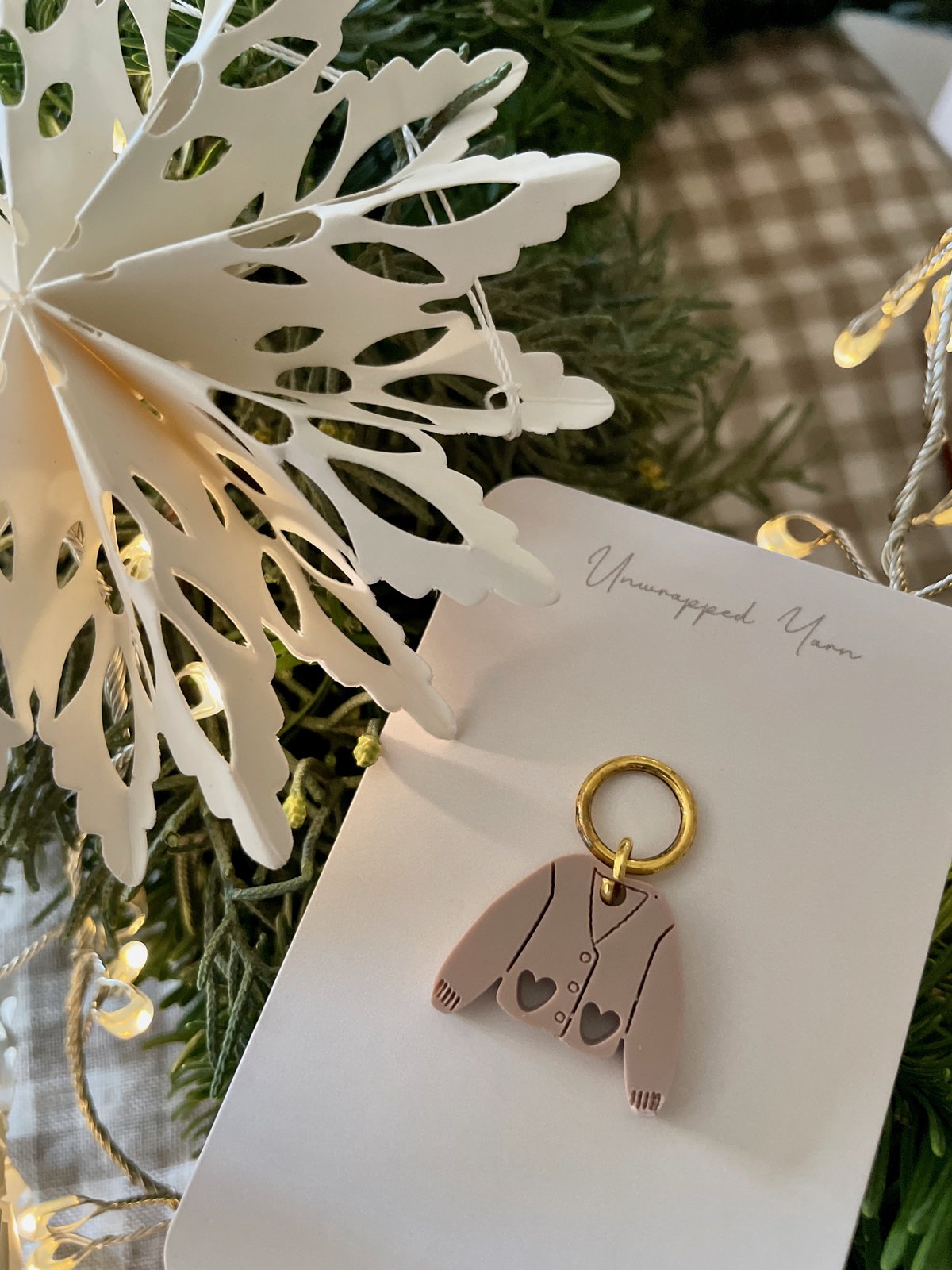 Soft pink yarn ornament with heart details and gold hoop, perfect for cozy holiday decorations.