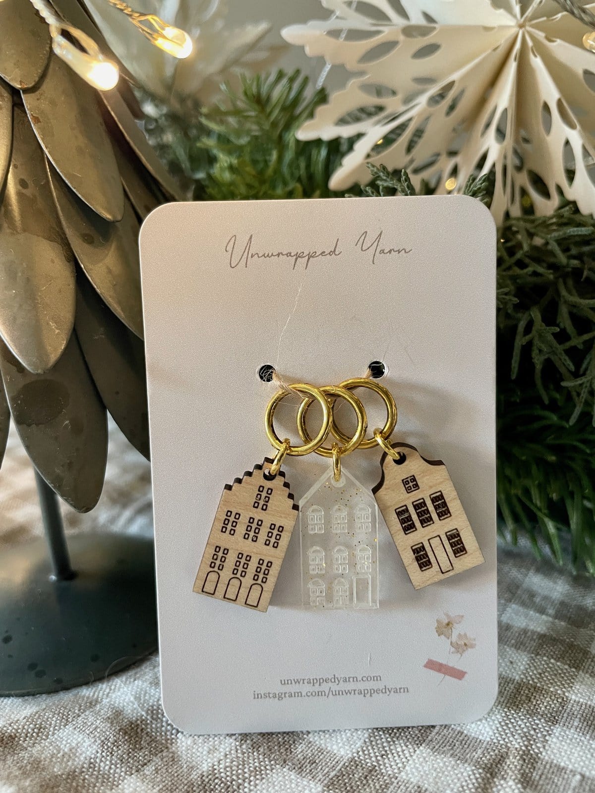 Delicate house-shaped earrings on a jewelry card, featuring gold hoops and layered building designs.