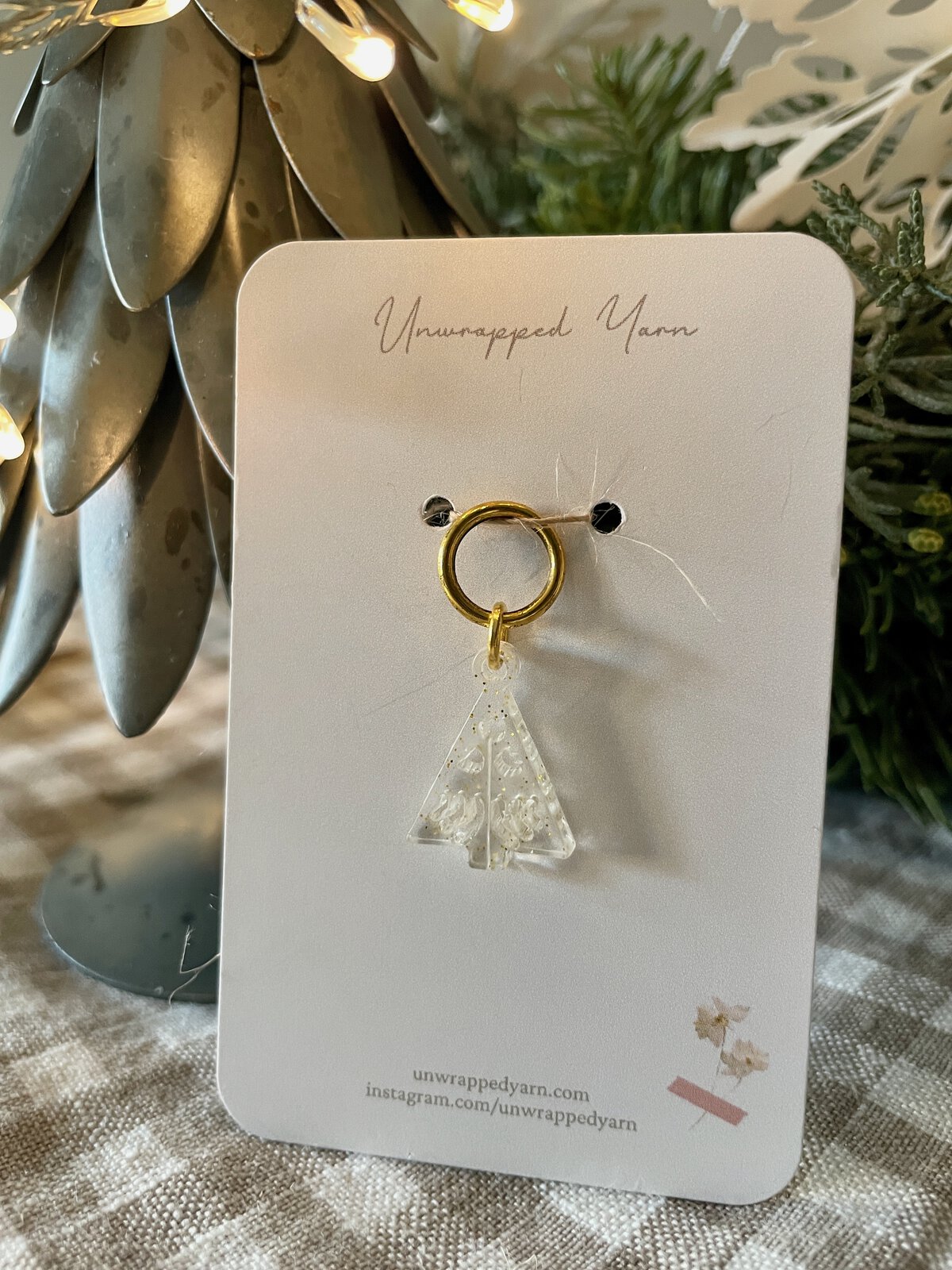 Delicate acrylic Christmas tree jewelry accessory on gold hoop, perfect for festive holiday style.
