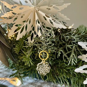 Delicate snowflake charm on a festive greenery arrangement, perfect for holiday cheer and Christmas decor.